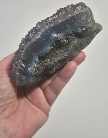Drusa Natural de Ametista com cristais violeta e formação mineral exclusiva fotografada na mão