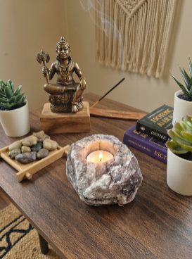 Porta-velas em Quartzo Hematoide Natural com vela acesa sobre mesa de madeira.